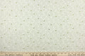 This quilting fabric feature  a Downtown Abbey print with a bit of holly in green against a white background .