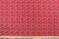 This fabric features a whimsical vine and floral design in white set against a red background.