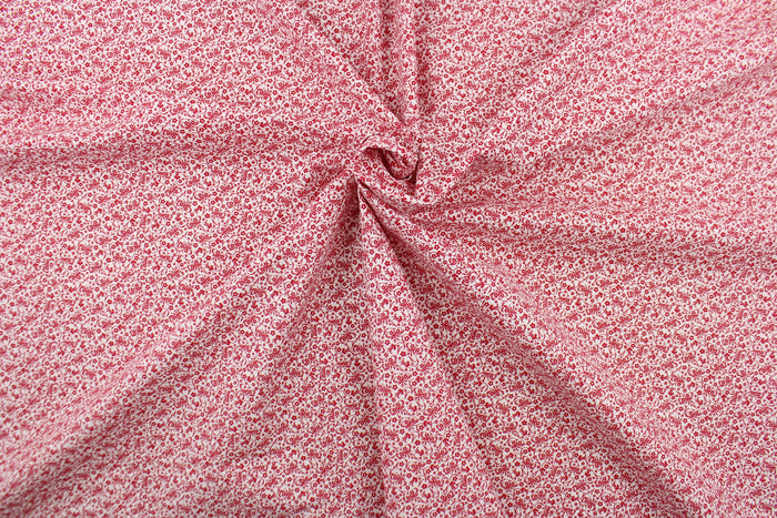 This fabric features a tiny floral design in red set against a white background.