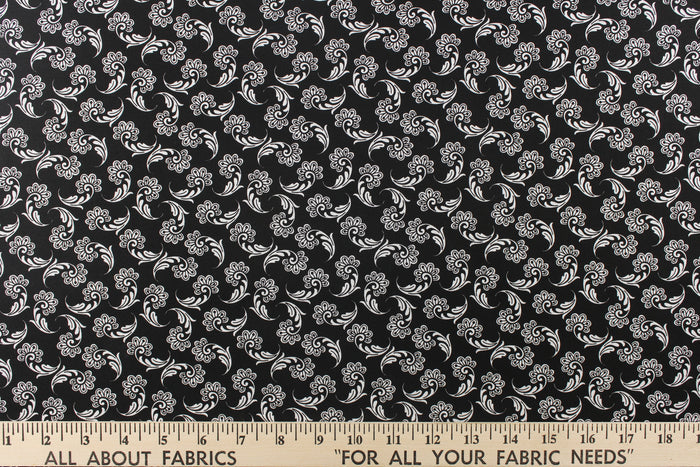 This fabric features a whimsical floral design in white on a black background.
