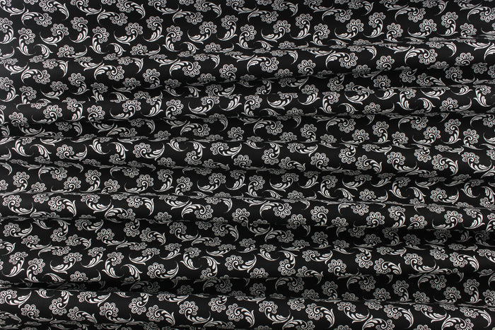 This fabric features a whimsical floral design in white on a black background.