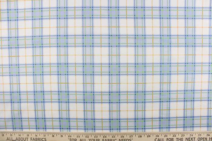 This quilting print features a plaid design in blue, white, green, and a orangey yellow.