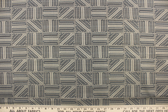 This high end upholstery weight fabric features a geometric design in blue and beige on a metal gray background.  It is suited for uses that requires a more durable fabric.  The reinforced backing makes it great for upholstery projects including sofas, chairs, dining chairs, pillows, handbags and craft projects.  It is soft and pliable and would make a great accent to any room.