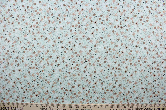 Cicely features an intricate floral pattern in shades of brown, tan, white, and black, set against a light green background.  The high-quality cotton material ensures lasting durability and softness.  It would be great for apparel, quilting, crafting and sewing projects.