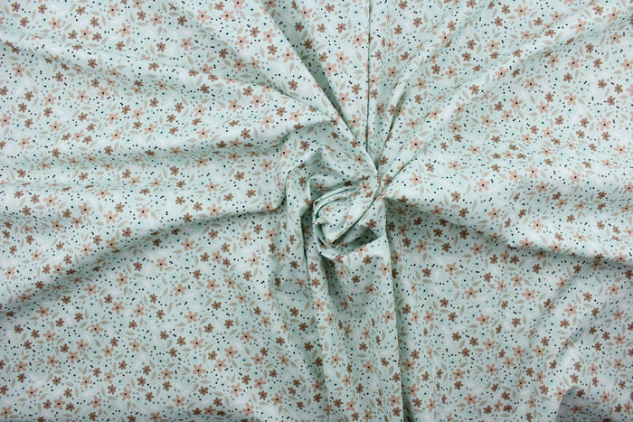 Cicely features an intricate floral pattern in shades of brown, tan, white, and black, set against a light green background.  The high-quality cotton material ensures lasting durability and softness.  It would be great for apparel, quilting, crafting and sewing projects.