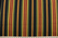 This Richloom© Lyndhurst in Raven multipurpose outdoor fabric adds a unique style to any space, featuring stripes of green, black, yellow, brick red, and goldenrod.  Durable and long-lasting, it is rated for 10,000 double rubs.  Can withstand up to 500 hours of direct sunlight, it is also water and stain resistant.  Perfect for patio, deck and poolside.  It can be used for several different statement projects including cushions, upholstery projects and decorative pillows.