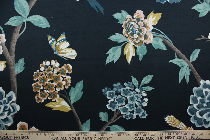 a multi-purpose fabric  designed with a large scale floral print featuring perched birds and butterflies in slate blue, pale pink, golden yellow, green, white, tan, and brown against an admiral blue background. The fabric is also incredibly durable, offering up to 30,000 double rubs.  It can be used for several different statement projects including window accents (drapery, curtains and swags), toss pillows, headboards, bed skirts, duvet covers, upholstery, and more.
