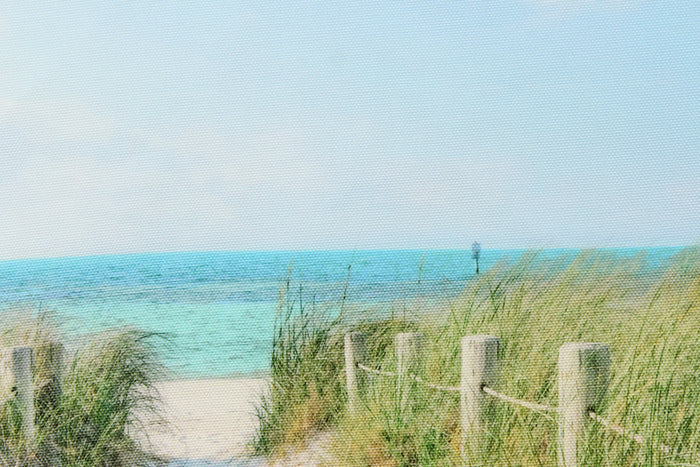 This fabric features a beautiful realistic view of a boardwalk out through the sand dunes to the ocean in beige, blue, green and gray.
