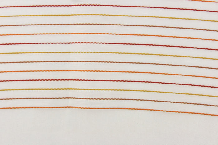 This sheer fabric features a stripe design in orange, brown, red, and golden yellow  against white.