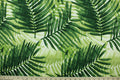 This outdoor fabric features a tropical leaf design in shades of green set against a white background.