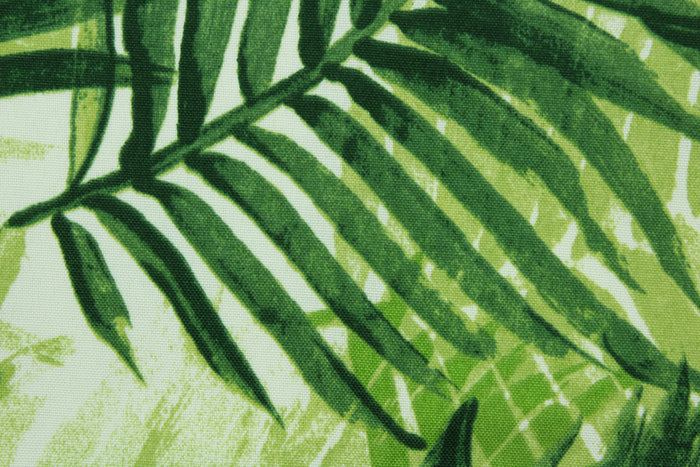 This outdoor fabric features a tropical leaf design in shades of green set against a white background.