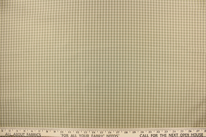 This yarn dye stripe fabric features a small plaid or checkered design in light khaki and pale green.